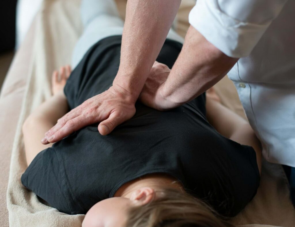 En kiropraktor i Huddinge masserar en patients mellersta rygg.