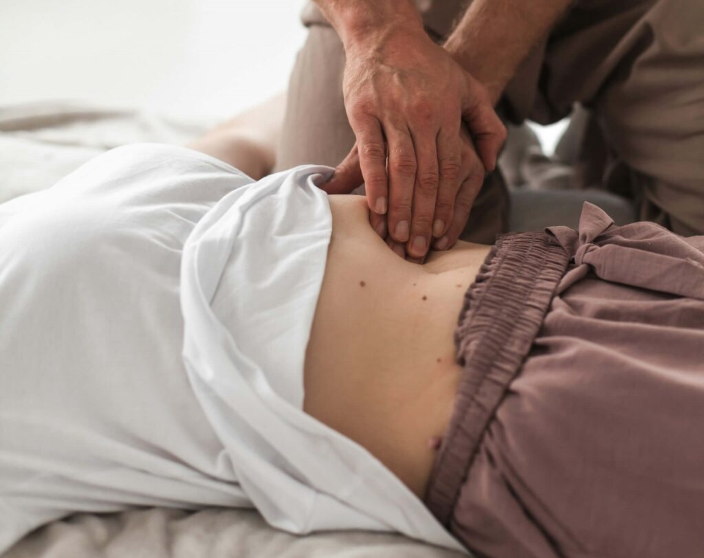 En kiropraktor i Nynäshamn behandlar en patients mage genom att massera.